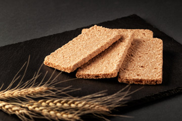 Crispy rye bread on a serving board with rye ears