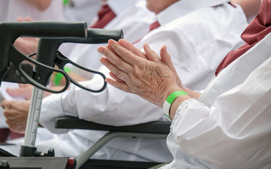 Nahaufnahme von H&auml;nden einer Seniorin in der Gruppe und Rollator im Vordergrund - selektiver Fokus