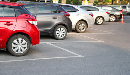 Closeup of rear, back side of red car with  other cars parking in outdoor parking area in bright sunny day. 