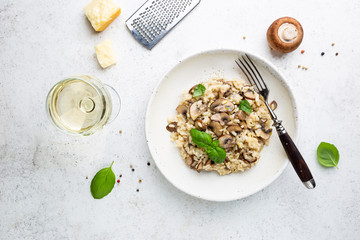Risotto with mushrooms in a white plate over white background, top view