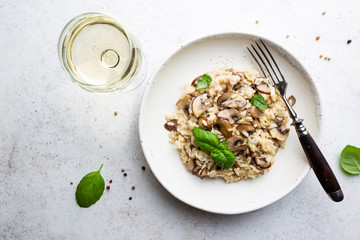 Risotto with mushrooms in a white plate over white background, top view