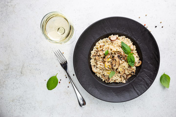 Risotto with mushrooms in a black plate over white background, top view