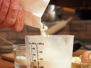 Pouring flour into measuring cup. Making yeast pancakes (crepes).