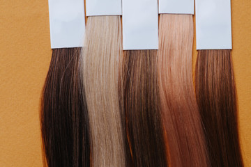 Close up image of dyed hair locks. Samples in a row over orange.