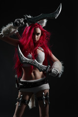 Sexy redhead woman in cosplay costume of warrior cat with swords posing on dark background - obrazy, fototapety, plakaty