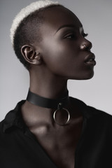 Sensual african american woman wearing leather choker posing on light grey background