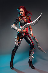 Fearless redhead warrior woman in leather costume with swords posing on dark background