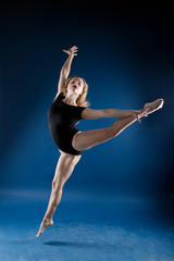 girl dancer in a jump and a beautiful pose on a blue background