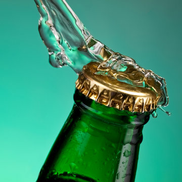 Top Of Beer Bottle With Water Splash On Green Background