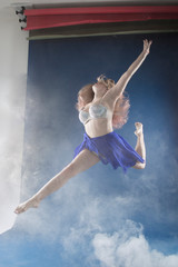 girl dancer in a jump and a beautiful pose on a blue background