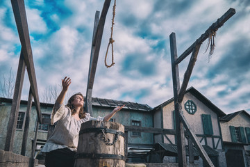 Woman raises her hands to the sky at the place of execution, the area with the gallows at the scaffold - obrazy, fototapety, plakaty