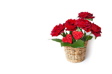 Fototapeta na wymiar Red roses and heart candies in a wicker basket on a white isolated background. Greeting card.