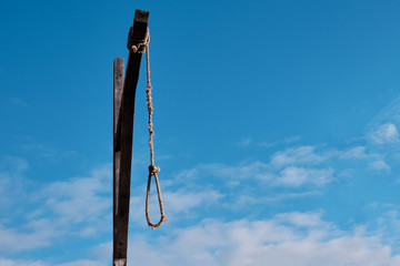 Fototapeta premium Wooden gallows with old rope and noose against cloudy sky