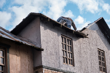 Man worker mends the roof of an old house in a medieval style.