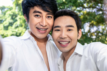 Fototapeta premium Young Asian homosexual couple taking self portrait with smart phone.Concept LGBT gay.