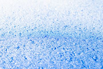 Texture of sparkling first cold ice. Blue snowy backdrop. Winter background for design. Abstraction in nature.