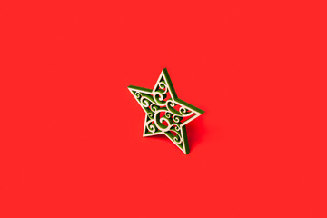 Decorative Christmas star made of wood with green patterns isolated on red background