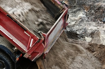 a dump truck unloads a load of sand on a construction site © gehapromo