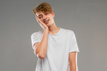 Young caucasian man in white t-shirt posing and gesticulating on camera isolated on grey background