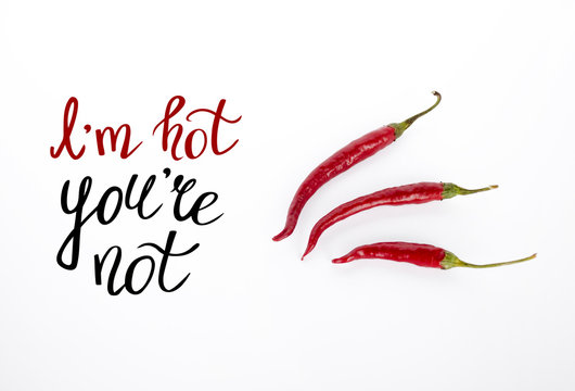 Red hot chili pepper with lettering isolated on the white background. I am hot, you are not. Funny phrase. Cayenne peppers, top view. Selective focus.