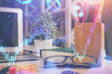 Financial chart hologram with glasses on the table background. Concept of business. Double exposure.