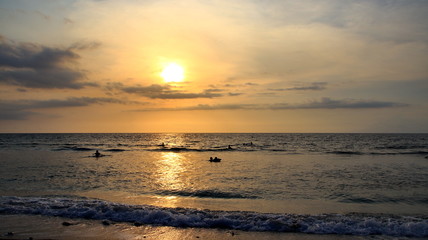 Documentation of surfers in action at dusk with a golden color and dark, unfocused and dark on the beach of Senggigi Lombok, West Nusa Tenggara Indonesia, 27 November 2019