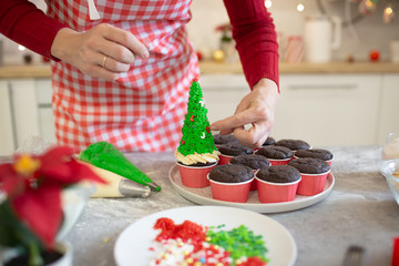Girl prepares cupcakes in the form of Christmas trees.