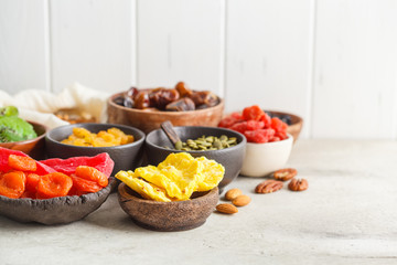 Variety of dry fruits and nuts in bowls, copy space. Healthy food concept, white background.