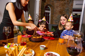 Portrait of happy multiethnic family celebrating a birthday at home. Big family eating cake and drinking wine while greeting and having fun children. Celebration, family, party, home concept.
