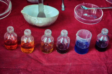 Obraz na płótnie Canvas Jars with colorful reagent in an old chemical laboratory. Chemicals in bottles with colored liquids. Table with tools and dies for chemical experiments in chemistry.