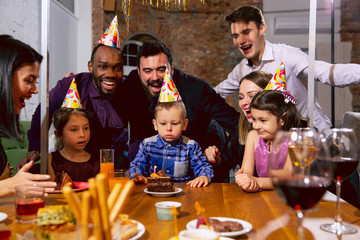 Portrait of happy multiethnic family celebrating a birthday at home. Big family eating cake and drinking wine while greeting and having fun children. Celebration, family, party, home concept.
