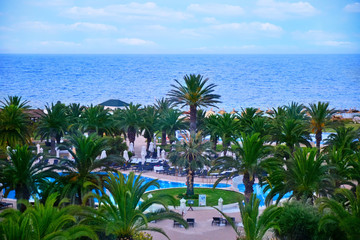 Fototapeta na wymiar Sea view, pool view, cloudy sky and palm trees. Tropical landscape on vacation