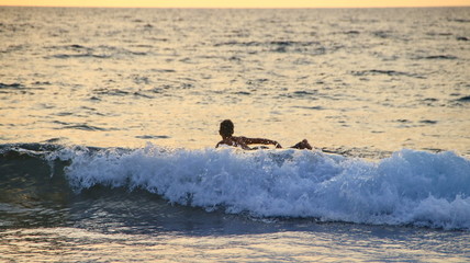 Documentation of surfers in action at dusk with a golden color and dark, unfocused and dark on the beach of Senggigi Lombok, West Nusa Tenggara Indonesia, 27 November 2019
