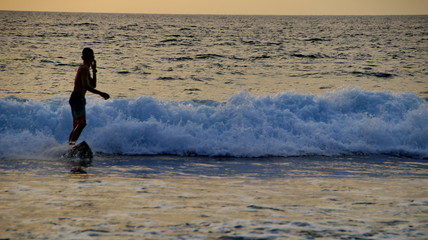Documentation of surfers in action at dusk with a golden color and dark, unfocused and dark on the beach of Senggigi Lombok, West Nusa Tenggara Indonesia, 27 November 2019