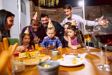 Portrait of happy multiethnic family celebrating a birthday at home. Big family eating cake and drinking wine while greeting and having fun children. Celebration, family, party, home concept.
