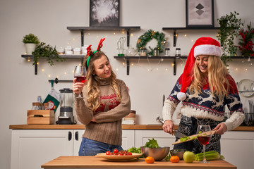 Women with glass and girl cuts celery for New Year in kitchen