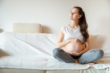 Young pregnant woman sitting on sofa