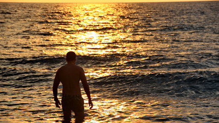 Documentation of surfers in action at dusk with a golden color and dark, unfocused and dark on the beach of Senggigi Lombok, West Nusa Tenggara Indonesia, 27 November 2019