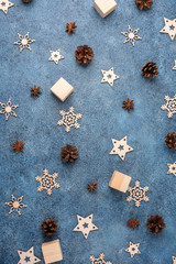 Fototapeta na wymiar Winter flat lay with cinnamon, anise, cones, wooden snowflakes on a blue textural background. Concept for Christmas and New Year.
