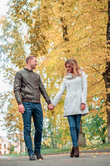 loving couple tenderly holding hands against the backdrop of an autumn park, the concept of romantic relationships and first love