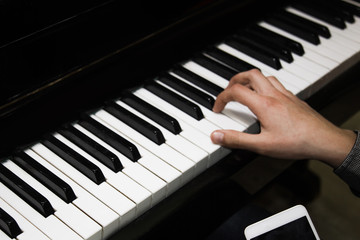 one male hand on the piano. The palm lies on the keys and plays the keyboard instrument in the music school. student learns to play. hands pianist. black dark background.