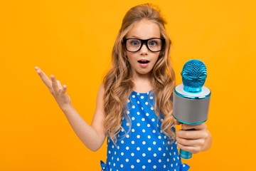 A little girl with glasses with a microphone is interviewed, the picture is isolated on yellow background