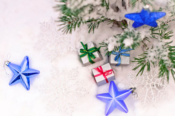 New Year's gifts in real snow on the street under a green holiday tree with blue toys stars