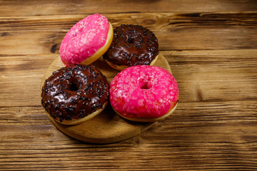 Tasty pink and chocolate donuts on a wooden table