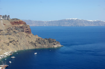 Fototapeta na wymiar Greece, Thirasia island. A lesser known hidden gem, quieter than the well know adjacent island of Santorini. A view of the port on a summers day. In the distance, at Santorini, is the town of Oia. 