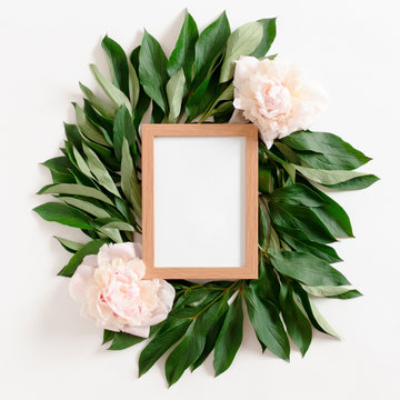 Wooden photo frame mockup with pink peonies and green leaves
