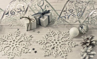 Christmas light gray background on wooden boards with tinsel, toys, silver stars, snowflakes and gifts.