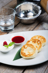 Traditional breakfast with coffee and cheesecakes, cottage cheese pancakes on a plate with syrup and jam.