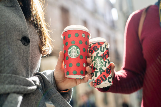 New York, USA - December 5, 2019 : Close up of a Two Young Business Woman Holding tall Christmas Starbucks Coffee on the street during sunset in New york. Starbucks is the world's largest coffee house
