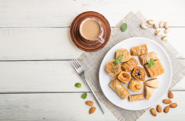 traditional arabic sweets (kunafa, baklava)  and a cup of coffee on a white wooden background. top view, copy space.